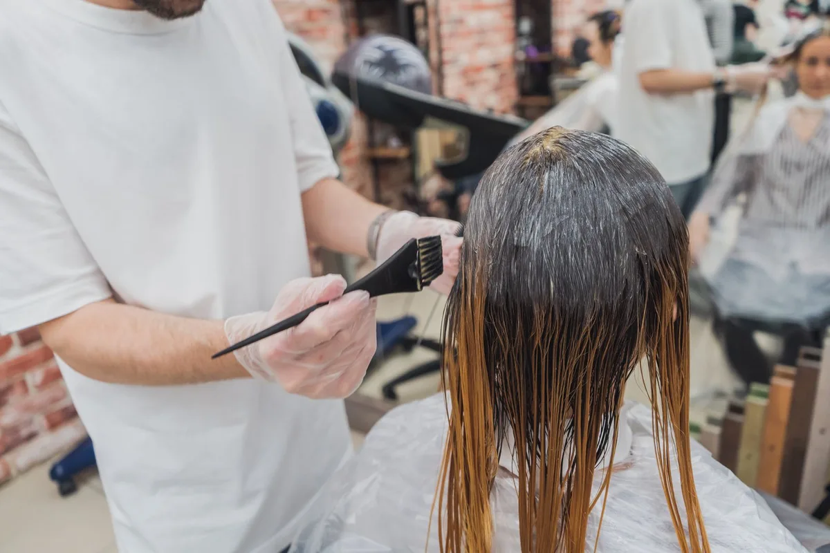 A Cardiff hair stylist carefully hand-painting balayage highlights onto a client's mid-length brown hair