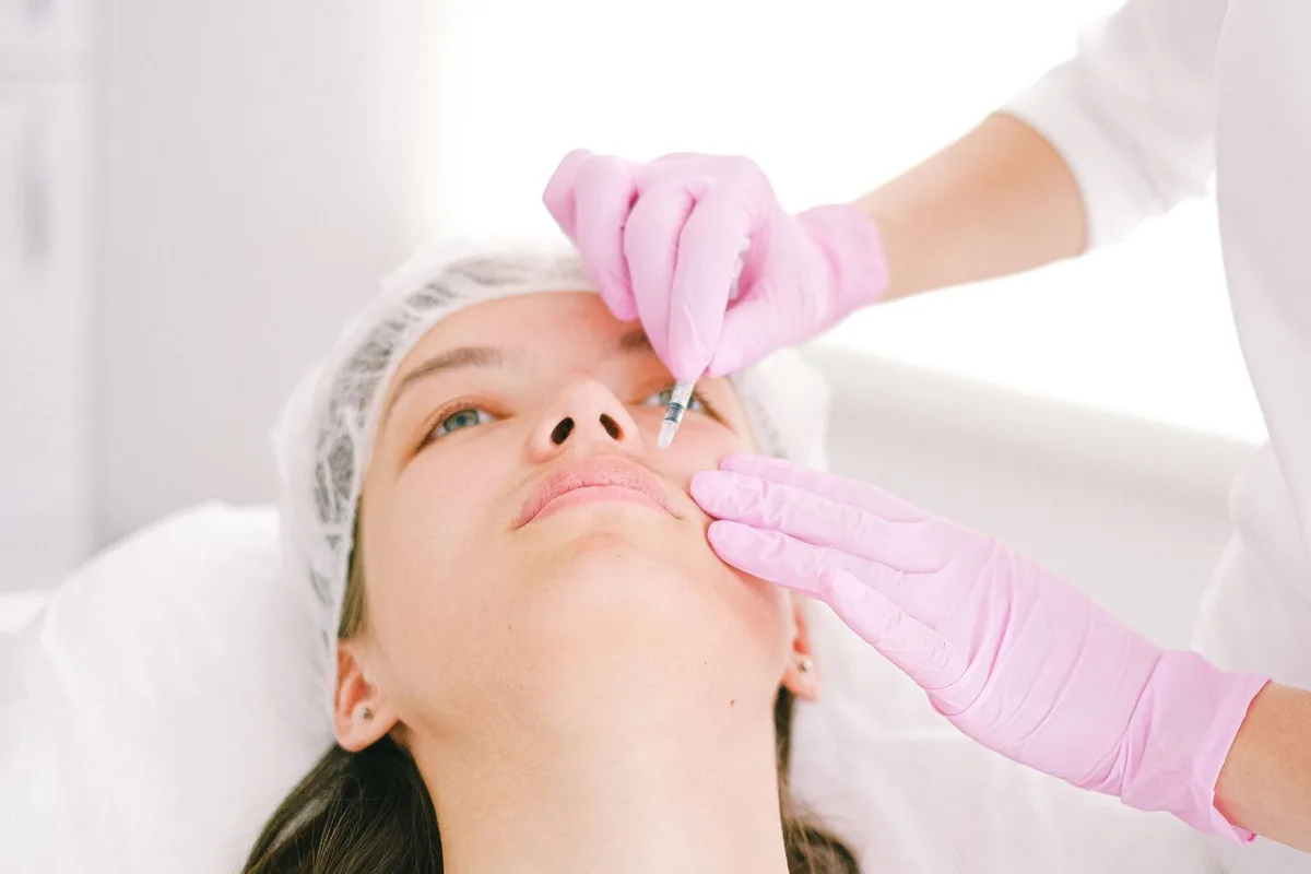 An aesthetics practitioner marking treatment zones on a client's cheeks and jawline before a dermal filler session at a Cardiff clinic
